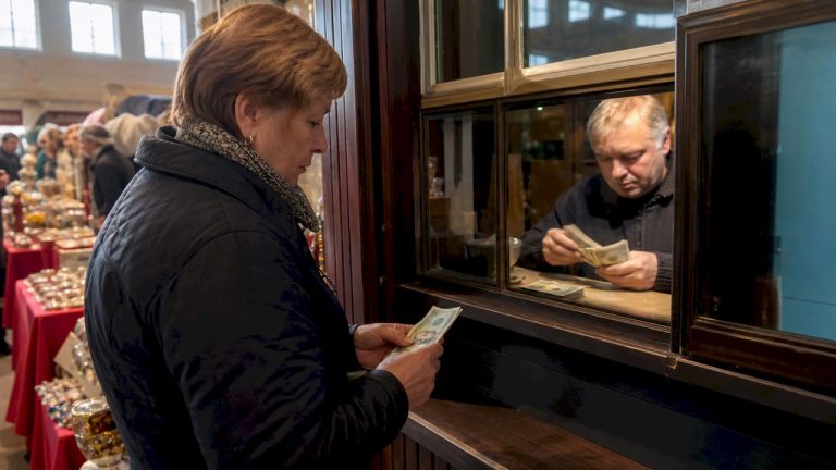 Moteris keičia pinigus valiutų keitykloje mieste.
