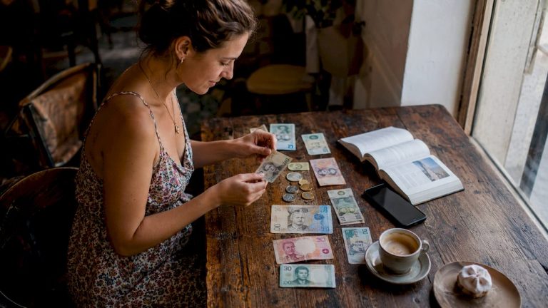 Kelionėje kavinėje keliautojas rūšiuoja užsienio valiutos banknotus.